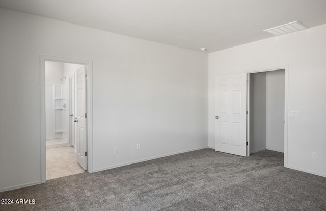 unfurnished bedroom with ensuite bath and light colored carpet