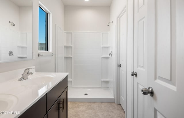 bathroom with a shower, tile patterned flooring, and vanity