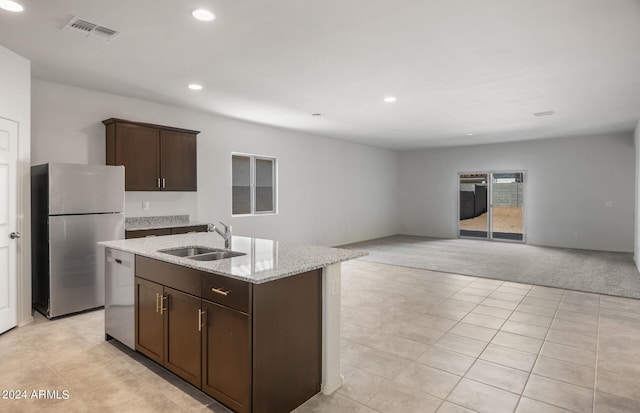 kitchen featuring sink, an island with sink, light colored carpet, stainless steel appliances, and light stone countertops