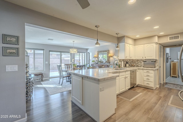 kitchen featuring hanging light fixtures, white cabinetry, sink, and kitchen peninsula