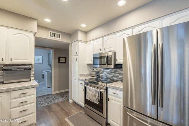 kitchen featuring separate washer and dryer, appliances with stainless steel finishes, white cabinets, and dark hardwood / wood-style flooring