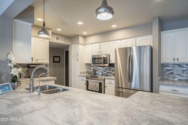 kitchen with pendant lighting, sink, appliances with stainless steel finishes, white cabinets, and decorative backsplash