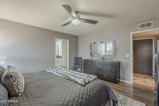 bedroom featuring connected bathroom, ceiling fan, dark wood-type flooring, and a textured ceiling