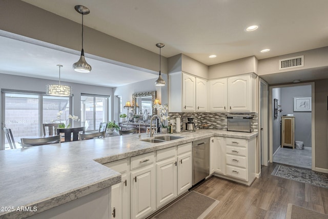 kitchen featuring sink, hardwood / wood-style flooring, decorative backsplash, white cabinets, and decorative light fixtures