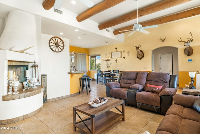 tiled living room featuring ceiling fan with notable chandelier and beam ceiling