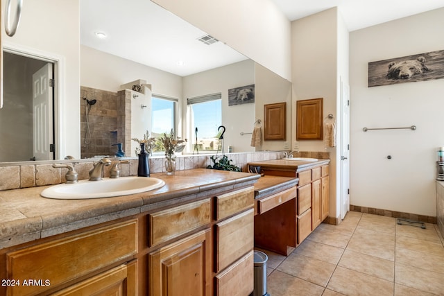 bathroom with a tile shower, tile patterned flooring, and vanity