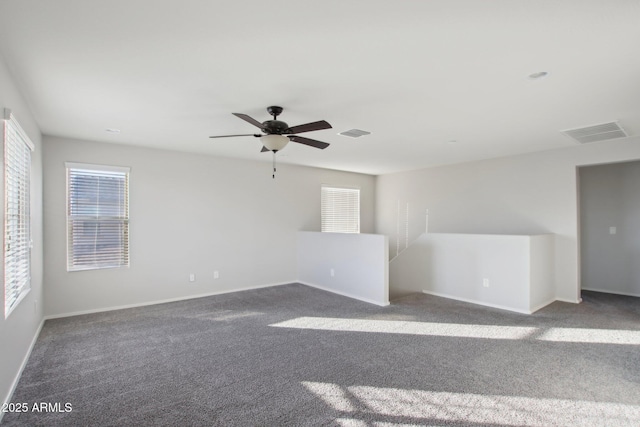 empty room featuring ceiling fan and dark colored carpet