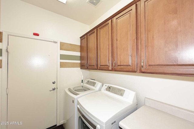 laundry area with washer and clothes dryer, visible vents, and cabinet space