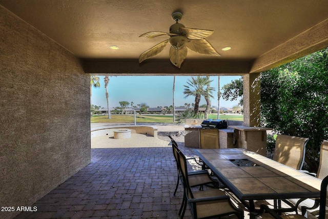 view of patio with area for grilling, outdoor dining space, and a ceiling fan