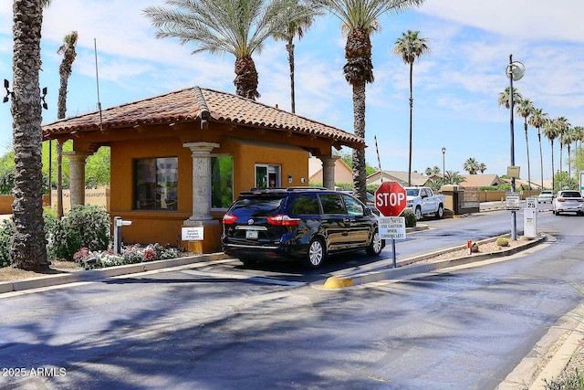 exterior space with traffic signs, curbs, and a gated entry