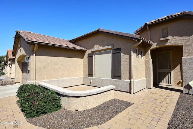 exterior space with stucco siding, a patio, and a tile roof