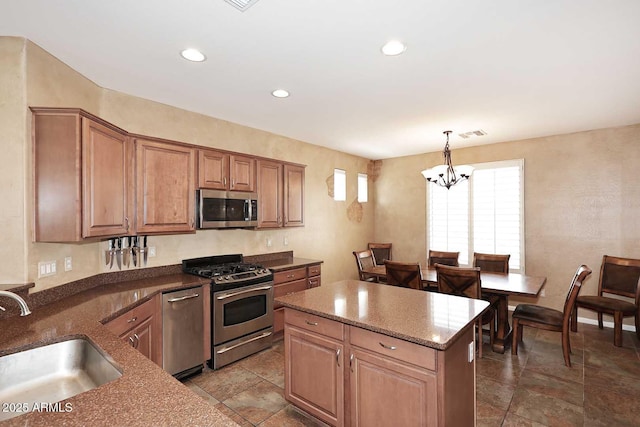 kitchen featuring a sink, dark stone countertops, a kitchen island, appliances with stainless steel finishes, and a chandelier