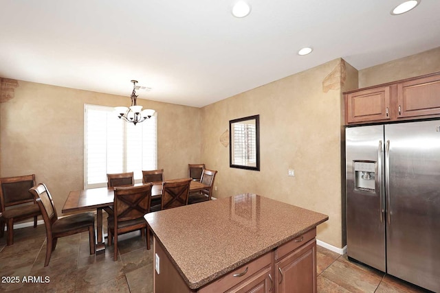 kitchen featuring pendant lighting, stainless steel refrigerator with ice dispenser, a center island, recessed lighting, and an inviting chandelier