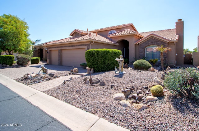 mediterranean / spanish-style house featuring a tile roof, concrete driveway, stucco siding, a chimney, and an attached garage