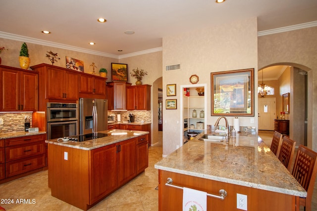 kitchen with a sink, light stone counters, a kitchen island, stainless steel appliances, and arched walkways