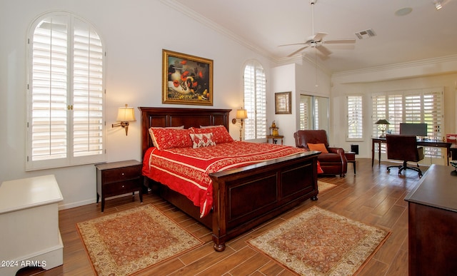 bedroom featuring wood finished floors, visible vents, baseboards, vaulted ceiling, and crown molding