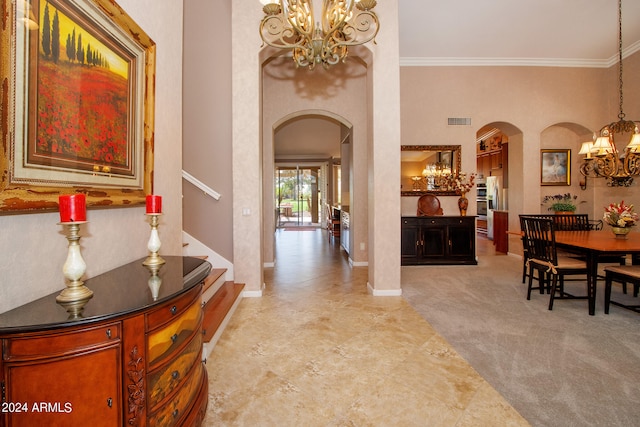 foyer entrance featuring visible vents, crown molding, a chandelier, stairs, and arched walkways