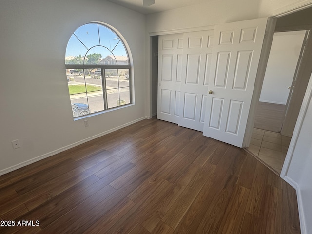 6416 N 78th Ln, Glendale, AZ 85303 - unfurnished bedroom featuring dark wood-type flooring, a closet, and baseboards