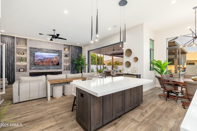 2656 E Oriole Dr, Gilbert, AZ 85297 - kitchen with dark brown cabinetry, light hardwood / wood-style floors, pendant lighting, a center island, and ceiling fan with notable chandelier
