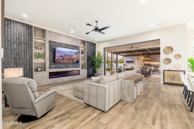 2656 E Oriole Dr, Gilbert, AZ 85297 - living room with a large fireplace, ceiling fan, built in features, and light hardwood / wood-style flooring