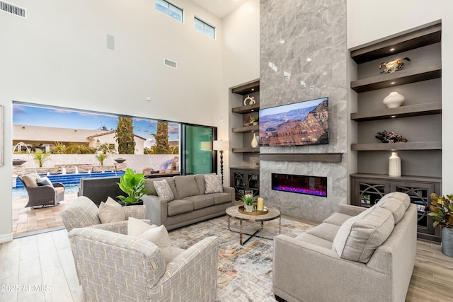 2656 E Oriole Dr, Gilbert, AZ 85297 - living room featuring a fireplace, a high ceiling, built in shelves, and light hardwood / wood-style floors
