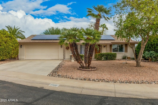 ranch-style home featuring driveway, an attached garage, a shingled roof, and solar panels