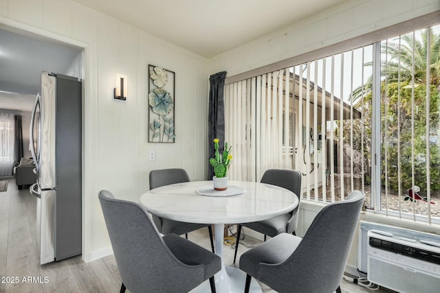 dining space featuring a wall unit AC and light wood-style flooring