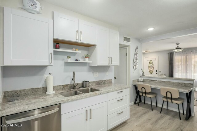 kitchen with visible vents, white cabinetry, a sink, light wood-type flooring, and dishwasher