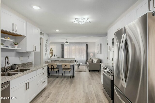 kitchen with stainless steel appliances, visible vents, light wood-style floors, open floor plan, and a sink