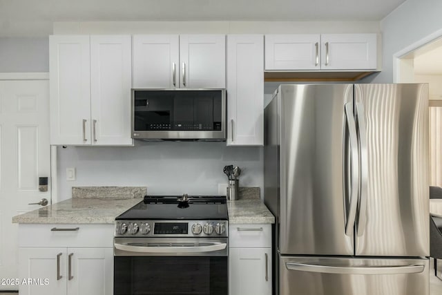 kitchen featuring stainless steel appliances, white cabinetry, and light stone counters