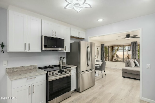 kitchen featuring baseboards, a ceiling fan, appliances with stainless steel finishes, light wood-type flooring, and white cabinetry