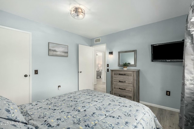 bedroom featuring visible vents, baseboards, and wood finished floors