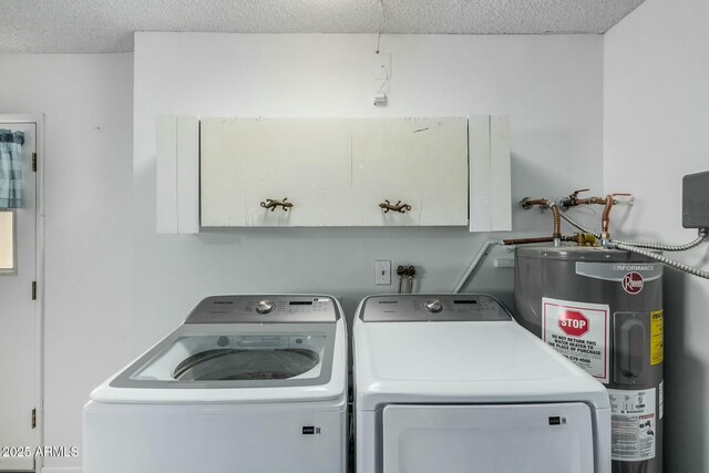 clothes washing area with washing machine and dryer, cabinet space, a textured ceiling, and water heater