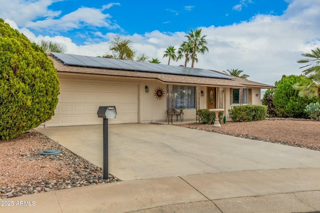 ranch-style house featuring driveway, an attached garage, and solar panels