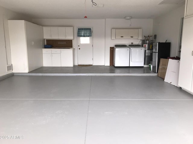 garage with water heater, freestanding refrigerator, visible vents, and independent washer and dryer