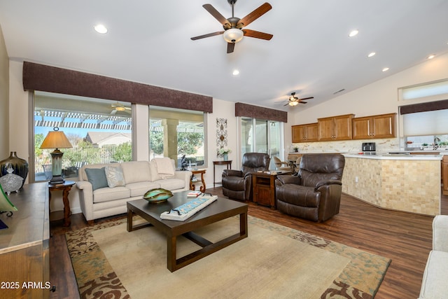 living room featuring hardwood / wood-style flooring, vaulted ceiling, sink, and ceiling fan