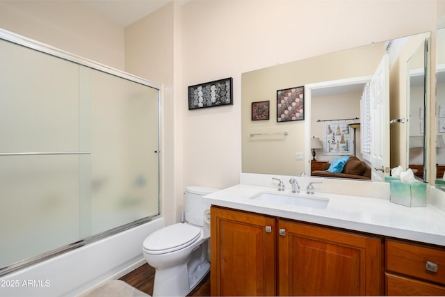 full bathroom featuring vanity, combined bath / shower with glass door, and toilet