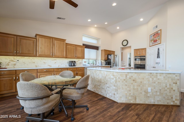 kitchen featuring appliances with stainless steel finishes, dark hardwood / wood-style floors, high vaulted ceiling, sink, and backsplash