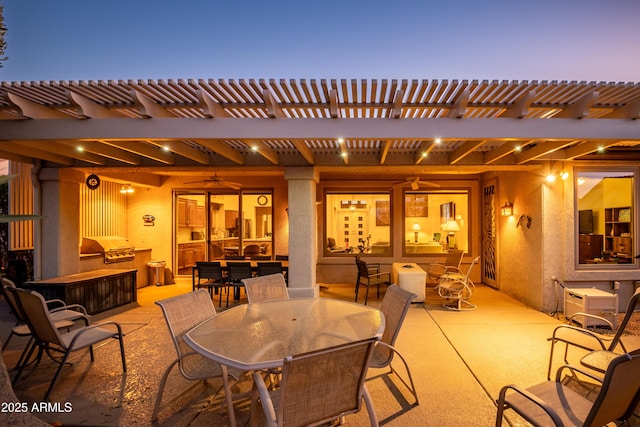 patio terrace at dusk with area for grilling and a pergola