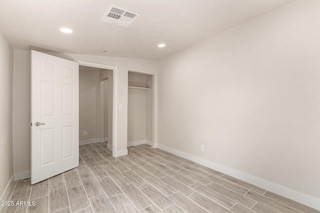 unfurnished bedroom featuring wood finish floors, visible vents, and baseboards