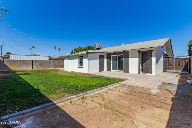 back of house featuring central AC, a lawn, a fenced backyard, and a patio