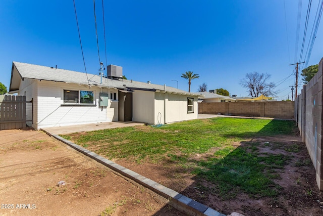 rear view of house with a yard, brick siding, a fenced backyard, and cooling unit