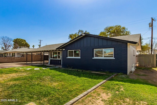 rear view of house featuring a patio area, fence, board and batten siding, and a yard