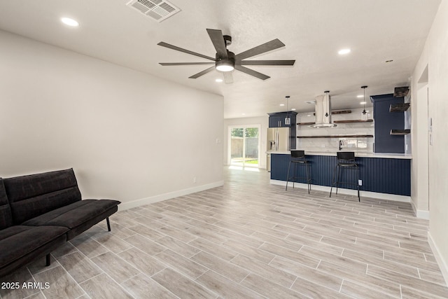 interior space with stainless steel refrigerator with ice dispenser, a breakfast bar area, open shelves, visible vents, and open floor plan