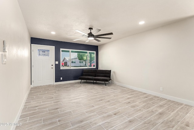 living area featuring light wood-style flooring, baseboards, and ceiling fan