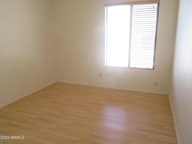 spare room with baseboards and light wood finished floors
