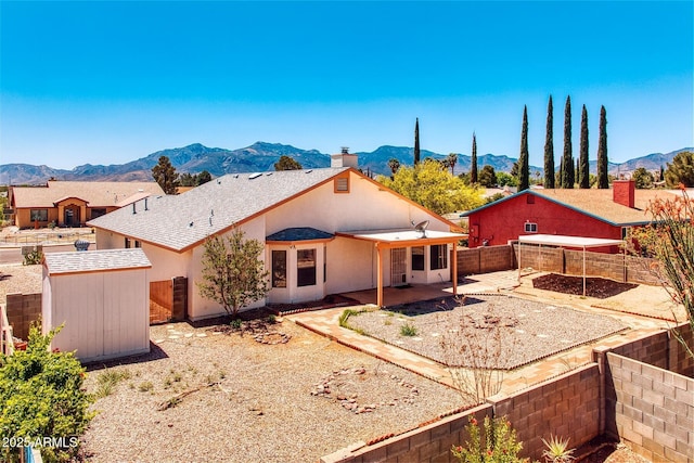 back of property featuring a fenced backyard, a storage unit, a patio area, a mountain view, and an outbuilding