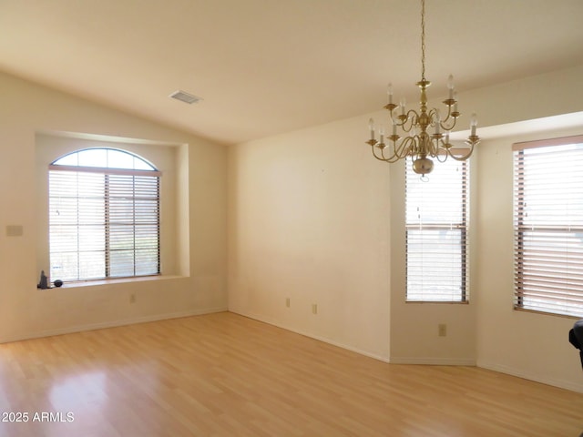 unfurnished room featuring visible vents, light wood finished floors, lofted ceiling, and a chandelier