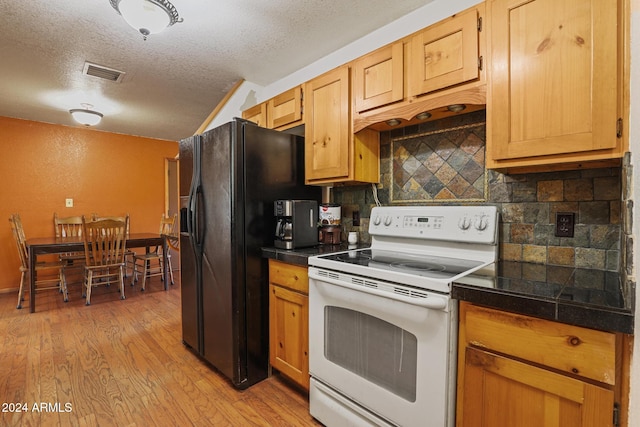 kitchen featuring black fridge, white electric range oven, light wood-type flooring, a textured ceiling, and decorative backsplash