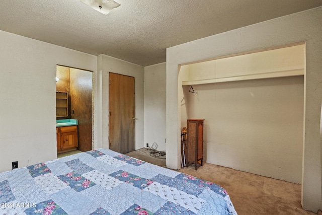 carpeted bedroom featuring a textured ceiling and ensuite bathroom